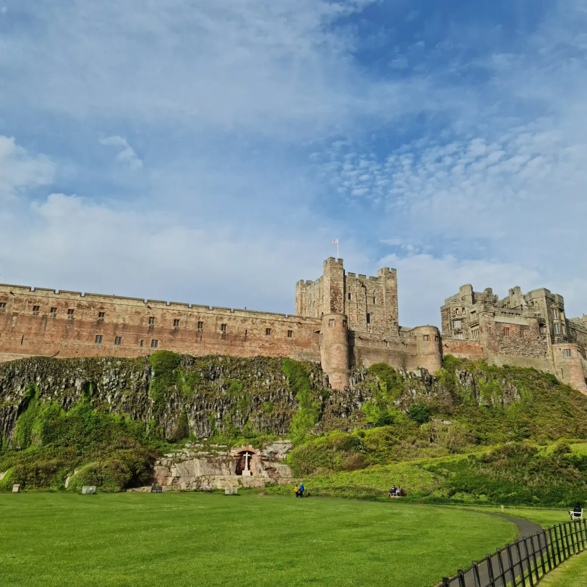 a castle on top of a grass covered field with Bamburgh Castle in the background